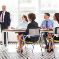 Smiling senior businessman conducting presentation in front of coworkers. Aged financial manager explaining new strategy to colleagues.
Business presentation concept